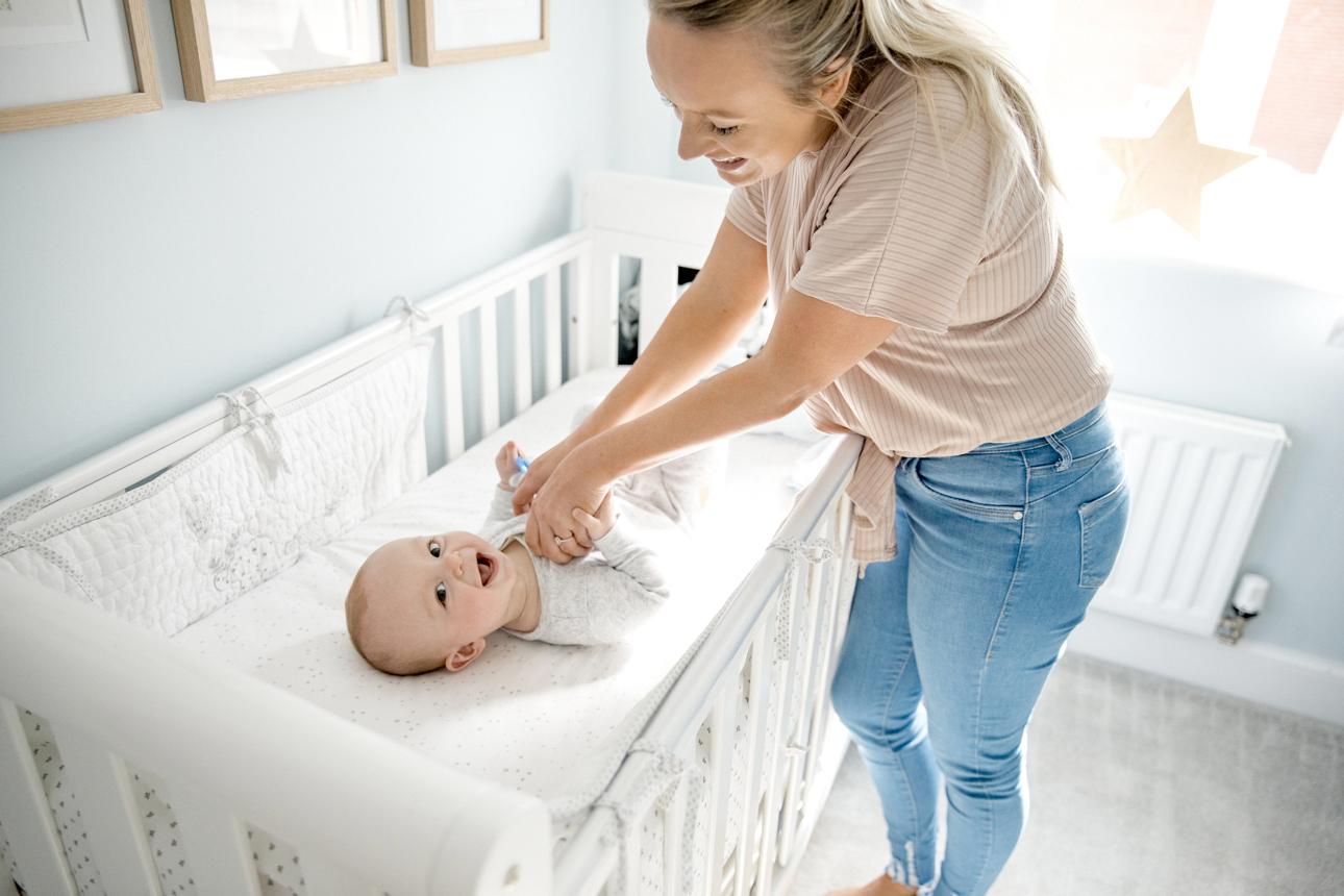 Parent gently placing sleeping baby into crib